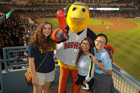 Students standing with Mud Hens mascot Muddy at a Mud Hens game